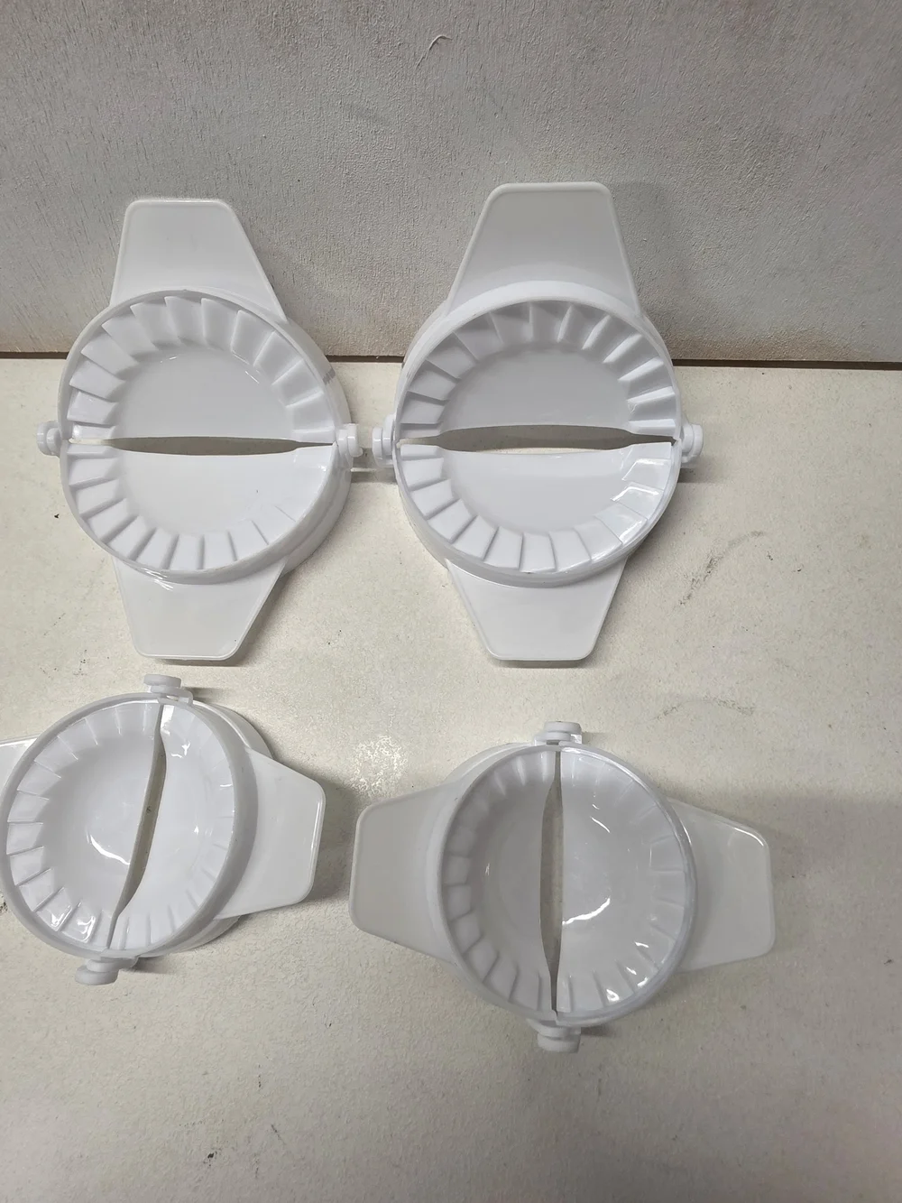 Set of 4 white plastic dumpling/empanada presses in two different sizes.